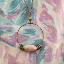 Load image into Gallery viewer, Necklace with a pink bead on a floral-patterned fabric background
